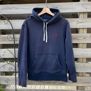 Ralph Lauren Hoodie Mörkblå - Mörkblå Ralph Lauren Hoodie i storlek S, passar XS/S. Den har inga hål eller fläckar, men den är lite urtvättad i färgen. På ryggen har den blivit lite solblekt, på bild 3 kan man se hur färgen är påväg att släppa. Jag rekommenderar köpare att använda mörkblå textilspray för att färga om,  eller färgmedel i tvätt. Borde gå att göra fin igen mer rätt utrustning! 