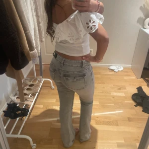 Grå bootcut jeans gina tricot - Säljer ett par ljusgrå jeans med bootcut-modell och hög midja. Jeansen har klassiska fickor bak och fram, samt snygga sömdetaljer. Materialet är jeans och passformen är normal med lätt utsvängda ben. Perfekta för dig som gillar en stilren och trendig look.