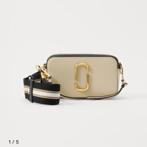 Marc Jacobs Snapshot axelväska beige - Marc Jacobs i färgen beige och svart på banden. I jättebra skick. Nypris 4495kr och säljer för 3000kr. 