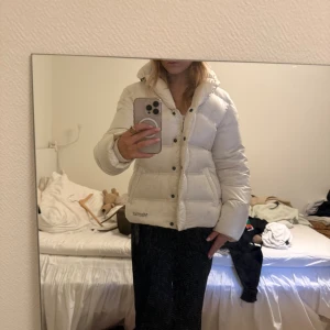 Vit pufferjacka från Marmot - Säljer en fluffig och varm vit pufferjacka från Marmot. Jackan har hög krage, svarta knappar och dragkedja, samt två fickor framtill. Perfekt för kalla dagar och har en riktigt snygg oversized vibe. Finns tydliga tecken på användning men fortfarande ingen man tänker på i första anmärkan. Ny pris runt 1500kr