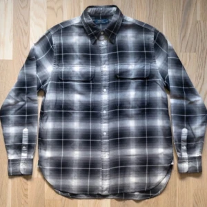 Flannelskjotra från Polo Ralph Lauren - Snygg rutig skjorta från Polo Ralph Lauren i svart, grått och vitt. Skjortan har klassisk krage, två bröstfickor med lock och knäppning framtill. Tillverkad i mjuk bomull och passar perfekt till en avslappnad stil. PASSAR S I STORLEK 