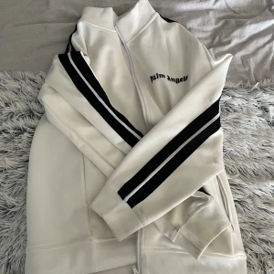 Vit Palm Angels ziptröja med svarta ränder - Säljer nu min vita palm angels hoodie då jag inte tycker om den, den är nästan oanvänd så den är i väldigt bra skick. Priset är diskuterbart vid snabb affär