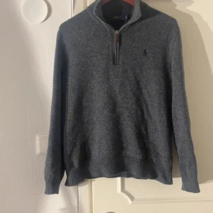 Grå stickad tröja från Polo Ralph Lauren - Mörkgrå stickad tröja från Polo Ralph Lauren med half zip, riktigt snygg och perfekt för vintern. Hör av er vid frågor!