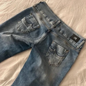 Blå jeans från LTB med raka ben - Snygga blå jeans från LTB med raka ben och klassisk femficksdesign. Jeansen har ljusa slitningar och detaljerade sömmar vid fickorna 