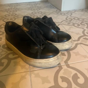 Svarta sneakers från Eytys - Svarta sneakers från Eytys med platt vit sula och lila detalj baktill. Skorna har snörning och är tillverkade i skinn. Klassisk rund tå och diskret logga på hälen. Perfekta för dig som gillar stilrena och chunky sneakers. alla är lånade bilder från hon jag köpte ifrån. skorna ser exkat ut så och jag  själv har inte använt dem.