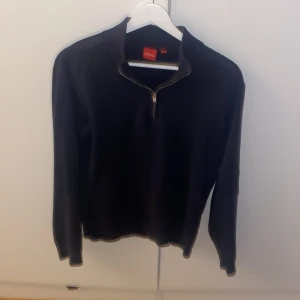 Svart stickad tröja med half zip - Svart stickad tröja från Ryvls med halv dragkedja vid halsen. Tröjan har långärmad design och en klassisk passform som funkar perfekt till kyligare dagar. Enkel och stilren look som passar till det mesta.