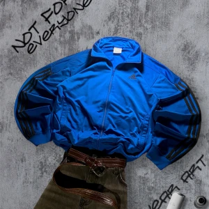 Blå Adidas tröja med svarta ränder - Säljer en blå tröja från Adidas med klassiska svarta ränder längs ärmarna och Adidas-logga på bröstet. Jackan har dragkedja framtill, ståkrage och två sidofickor. perfekt för en sportig look. Passar L 