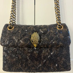 TILLFÄLLE Svart paljettväska från Kurt Geiger - !NYSKICK! Snygg svart axelväska från Kurt Geiger med glittriga paljetter och en unik guldfärgad kedja. Väskan har ett coolt fågelspänne framtill och detaljer i antikguld. Perfekt för dig som vill ha en väska som verkligen lyfter upp outfiten. Eftersom väskan har neutrala färger passar den till alla sorters outfits. Den är helt perfekt storlek! Hör mer än gärna av dig vid frågor/intresse!