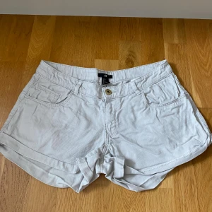 Vita shorts från H&M, strl 36 - Snygga vita shorts från H&M i storlek 36. Modellen har klassisk femficksdesign, knapp och dragkedja framtill samt uppvikta benslut. Gjorda i mjuk bomull med bälteshällor och normal passform. Perfekta för varma dagar och chill stil.