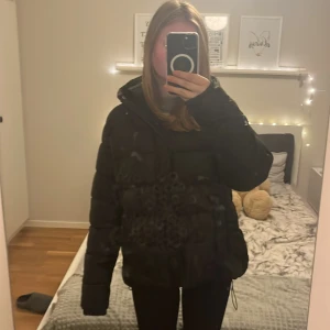 Svart pufferjacka från High Mountain🤍 - Svart pufferjacka från High Mountain med huva och dragkedja. Jackan är vadderad och har en lite oversized passform, perfekt för kalla dagar. Snygg och enkel design med två fickor framtill och justerbar nederkant med snörning. 