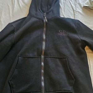 Svart hoodie med goggles från C.P. Company - Säljer denna Cp.Company Hoodie med glasögon, säljs då den är för liten. Använd 3 gånger, skriv om frågor o kan gå ner i pris.