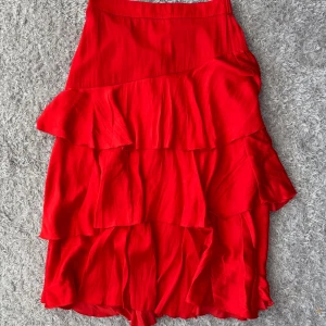 Röd volangkjol från Gina Tricot - Jättefin röd kjol med volanger. Från Gina Tricot, i storlek 38. Använd men som ny!