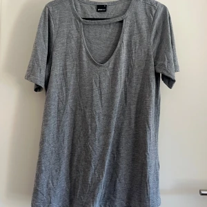 Grå t-shirt med cutout - Grå t-shirt från Gina Tricot i mjuk bomull. Modellen har korta ärmar och en snygg cutout-detalj vid halsringningen. 