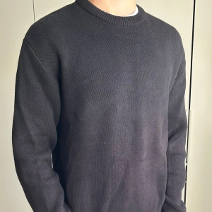 Svart stickad tröja - En enkel och stilren svart stickad tröja med rund halsringning. Tröjan är från Weekday och har långa ärmar och ribbade muddar. Perfekt att slänga på sig när det är kyligt ute. Storlek: M. Modellen är 190cm, 78kg. Skriv om ni har några som helst funderingar:)