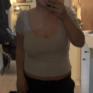 Ljus lila ribbad topp med djup rygg - Säljer en ljus lila  ribbad topp med korta ärmar och djup urringning både fram och bak. Toppen är figurnära och har en enkel, stilren design som passar perfekt till jeans eller kjol. Materialet är stretchigt och bekvämt.