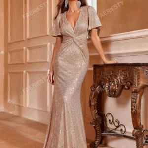 Glittrig champagnefärgad långklänning - Superelegant långklänning i champagnefärg med glittriga paljetter, v-ringad omlottfront och korta vida ärmar. Klänningen har figurnära passform och markerad midja som ger en snygg siluett. Perfekt för dig som vill sticka ut med stil. Klänningen är använd en gång på bal den är köpt för 550kr