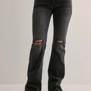 Svarta bootcut jeans med slitna knän - Snygga svarta jeans med bootcut passform och slitna detaljer vid knäna. Jeansen har klassiska fem fickor och coola sömmar på bakfickorna. Perfekt för dig som gillar en avslappnad och trendig stil. Från Nelly, nypris 699💕