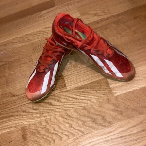 Adidas Crazyfast orange fotbollsskor - Säljer ett par ganska använda orange Adidas Crazyfast fotbollsskor med vita detaljer och snörning. Som ni ser på bilden så är skorna ganska smutsiga på grund av spel på konstgräs, men det går o tvätta dem. Skorna har låg profil, platt sula med dobbar i gult och vitt, samt klassiska tre ränder på sidorna. 