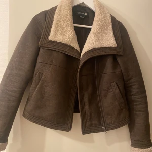 Jacka från Forever 21 - Säljer en brun faux läderjacka från Forever 21 med teddy krage. Jackan har silver dragkedja framtill, två fickor och är i ett syntetmaterial som ser ut som mocka. Är i storlek S men är lite tight i ärmarna, så skulle säga att det mer är XS🥰