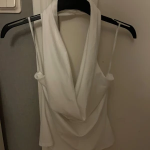 Vit topp djup urringning - Säljer en vit  linnetopp med djup v-ringad urringning och öppen rygg. Toppen har en snygg draperad front som ger en cool och trendig look. Perfekt för dig som gillar stilrena och enkla plagg med lite edge. Från Missäy och passar mig som bär XS/S❣️❣️aldrig använd 
