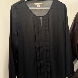 Svart blus från Anna Field - Säljer en svart blus från Anna Field med rund halsringning och långa ärmar. Framsidan har snygga veckade detaljer som ger en stilren look. Perfekt att matcha med jeans eller kjol för en clean outfit.