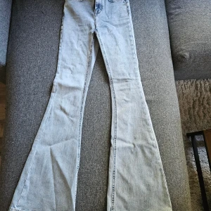Ljusblå bootcut jeans från Bubbleroom - Snygga ljusblå jeans från Bubbleroom med bootcut-modell och hög midja. Jeansen har klassiska fem fickor, bälteshällor och är tillverkade i mjukt denimtyg. Perfekta för dig som gillar retrovibbar och vill ha en cool siluett. Använda 1 gång, nypris 499kr.