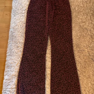 Glittriga leopardmönstrade byxor från Nomi - Säljer ett par svarta byxor från Nomi med glittrigt rosa leopardmönster. Byxorna har en rak och något utsvängd passform med resår i midjan för extra komfort. Perfekta för dig som vill sticka ut med ett coolt mönster och lite extra glitter.