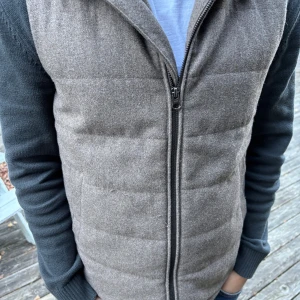 John Henric dun väst  - Snygg grå dunväst från John Henric med quiltad design och rak passform. Västen har ståkrage, två sidofickor och hel dragkedja framtill.