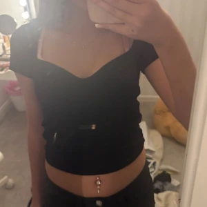 Svart croppad topp med v-ringning - Säljer en svart croppad topp med snygg v-ringad hals och korta ärmar.