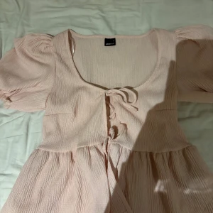 Ljusrosa topp  från Gina Tricot - Supersöt ljusrosa topp från Gina Tricot med puffärmar och knytning framtill. Perfekt för sommarens alla tillfällen och ger en romantisk vibe. Har bara provat 1 gång, pris kan diskuteras 