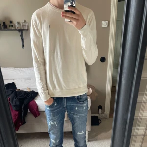 Vit stickad tröja från Ralph Lauren - Vit stickad tröja från Ralph Lauren med klassisk rund halsringning i helt nytt skick. Tröjan har lång ärm och är i mjuk bomull, perfekt för lager-på-lager och chill stil. Inga fel på tröjan har bara inte kommit till användning som jag hoppats, hör av dig!!