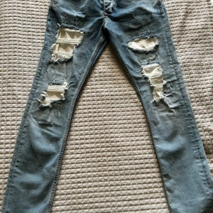 VSCT ljusblå ripped jeans 32/32 - Ljusblå jeans från VSCT Jeans med flera stora ripped detaljer och vita lappar under slitningarna. Klassisk femficksmodell med raka ben och snygga kontrastsömmar. Märkeslogga bak på fickan. 