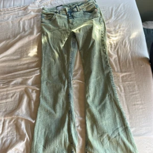 Monki ljusblå flared jeans low waist - Säljer ett par ljusblå jeans från Monki, modell Hatsumi med flared ben och låg midja. Jeansen är tillverkade i stretchigt material av återvunnen bomull och har klassisk femficksdesign. Perfekta för dig som gillar en retro vibe och vill ha bekväma jeans med snygg passform.