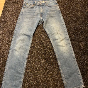 Weekday ljusblå jeans W28 L30 - Weekday jeans i ljusblå tvätt med raka ben och normal passform. Jeansen har fem fickor, knappgylf och subtila slitningar för en avslappnad look. Perfekta för dig som gillar tidlös denimstil.