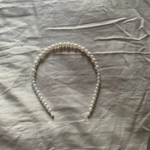Pärl-diadem i vit pärlemor - Snyggt diadem med glansiga vita pärlor i olika storlekar. Perfekt accessoar för att ge en elegant touch till din look. Diademet är böjt och sitter bekvämt på huvudet. Passar till både utsläppt och uppsatt hår.