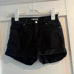 Svarta jeansshorts från H&M - Svarta jeansshorts från H&M i klassisk femficksmodell. De har hög midja, uppvikta benslut och stängs med knapp och dragkedja. 