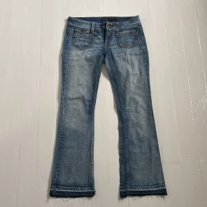 Blå bootcut jeans från Only - Snygga blå jeans från Only med bootcut passform och råa kanter nertill. Jeansen har klassiska fem fickor, ljus tvätt och kontrastsömmar. Perfekta för dig som gillar en avslappnad men trendig stil.