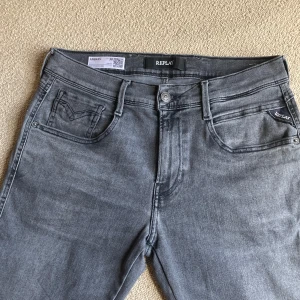 Replay Anbass grå jeans - Snygga grå jeans från Replay, modell Anbass. Klassisk femficksdesign med diskret Replay-logga på fickan och broderad bakficka. Jeansen har en rak passform och är tillverkade i mjukt denimtyg som ger en skön känsla hela dagen.