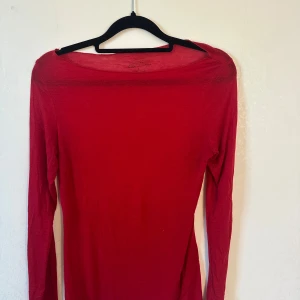 Röd långärmad tröja från Intimissimi - Superskön röd långärmad tröja från Intimissimi i ultralätt material med kashmir. Tröjan har en enkel, tight passform och rund halsringning. Perfekt att styla med jeans eller kjol för en clean look.