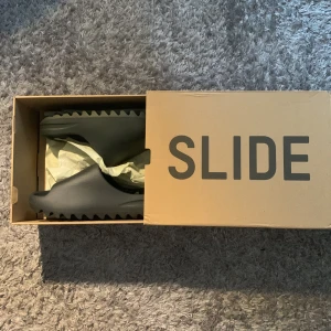 Adidas Yeezy Slide Onyx strl 42 - Säljer ett par Adidas Yeezy Slide i färgen Onyx. Slidesen är helsvarta, perfekta för chill dagar eller när du vill ha något bekvämt och stilrent på fötterna. Har bevis på att dom är äkta. Priset går att diskutera!