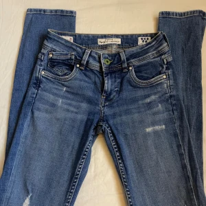 Blå jeans från Pepe Jeans - Blå jeans från Pepe Jeans med slitna detaljer, strl W9 (XS)