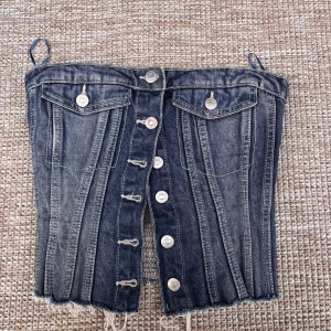 Jeanskorsett från Zara med knappar - Säljer en snygg jeanskorsett från Zara i mörkblå denim med silverfärgade knappar. Storlek xs