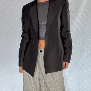 Svart kavaj med klassisk passform NA-KD stl.32/XXS - Snygg svart kavaj med dubbelknäppning och klassiska slag. Kavajen har en stilren, figurnära siluett och är tillverkad i ett slätt material som ger en elegant look. Perfekt att matcha med skjorta och svarta byxor för en clean outfit. 