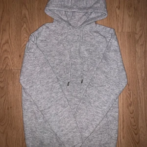 Grå Kashmir och merinoulls hoodie med snörning - En stilren grå Kashmir hoodie med huva och snörning framtill. Tröjan är långärmad och har ribbade muddar vid ärmslut och nederkant. Perfekt för chill dagar och enkel att matcha med jeans eller joggers.