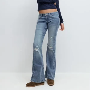 Blå bootcut jeans med broderade fickor - Snygga ljusblå bootcut jeans med slitningar på låren och broderade detaljer på bakfickorna. Jeansen har låg midja och klassisk femficksdesign. Perfekta för dig som gillar en avslappnad och trendig look. Helt nya