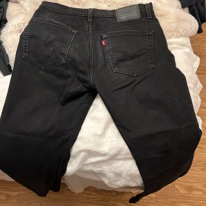 Svarta Levi's 514 jeans W32 L32 - Svarta Levi's 514 jeans med klassisk femficksdesign och raka ben. Jeansen har en mörk tvätt, tydliga sömmar och den ikoniska Levi's-lappen bak i midjan. Perfekt för dig som gillar en tidlös och clean look.