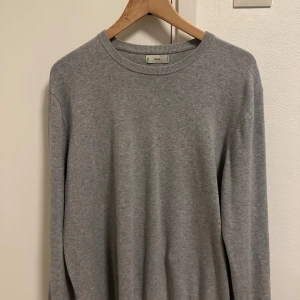 Grå bomullströja från MNG - En stilren grå tröja från MNG i mjuk bomull. Tröjan har rund halsringning, ribbade muddar och lång ärm. Perfekt för lager-på-lager och enkel att matcha med olika outfits. Tröjan har krymp så att den passar m/s