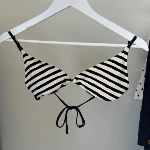Randig bikiniöverdel med knyt - Snygg bikiniöverdel med svartvita ränder och smala svarta band som knyts i ryggen. Klassisk trekantsform som ger en cool och fräsch strandlook. Perfekt för dig som gillar enkel och stilren design. Materialet känns mjukt och följsamt mot huden.