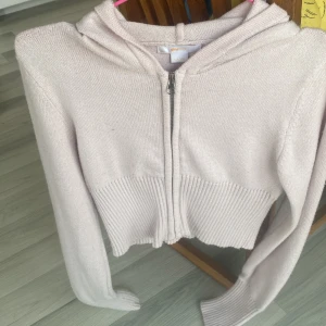 Ljusrosa stickad hoodie från Gina Tricot - Supersöt ljusrosa stickad hoodie från Gina Tricot med dragkedja framtill. Tröjan är croppad med bred ribbad midja och har långa ärmar samt huva. 