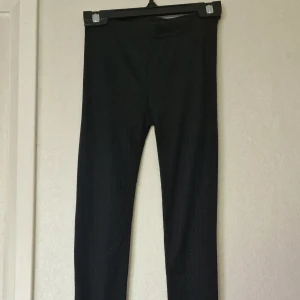 Svarta ribbade leggings från Mywear Active - Svarta ribbade leggings från Mywear Active i stretchigt material. De har en tight passform och elastisk midja, perfekta för en aktiv vardag eller chill hemma. Snygg ribbad struktur som ger en sportig vibe. Perfekta till lager på lager under kallare dagar. De är noppriga men i bra skick i övrigt.